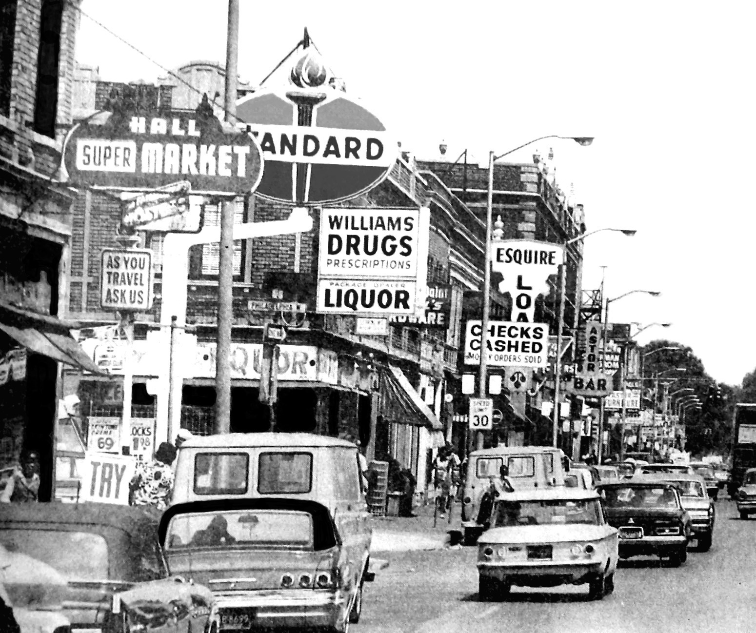 Black and white photograph of Black Bottom street scene from the 1940s with cars and street signs.