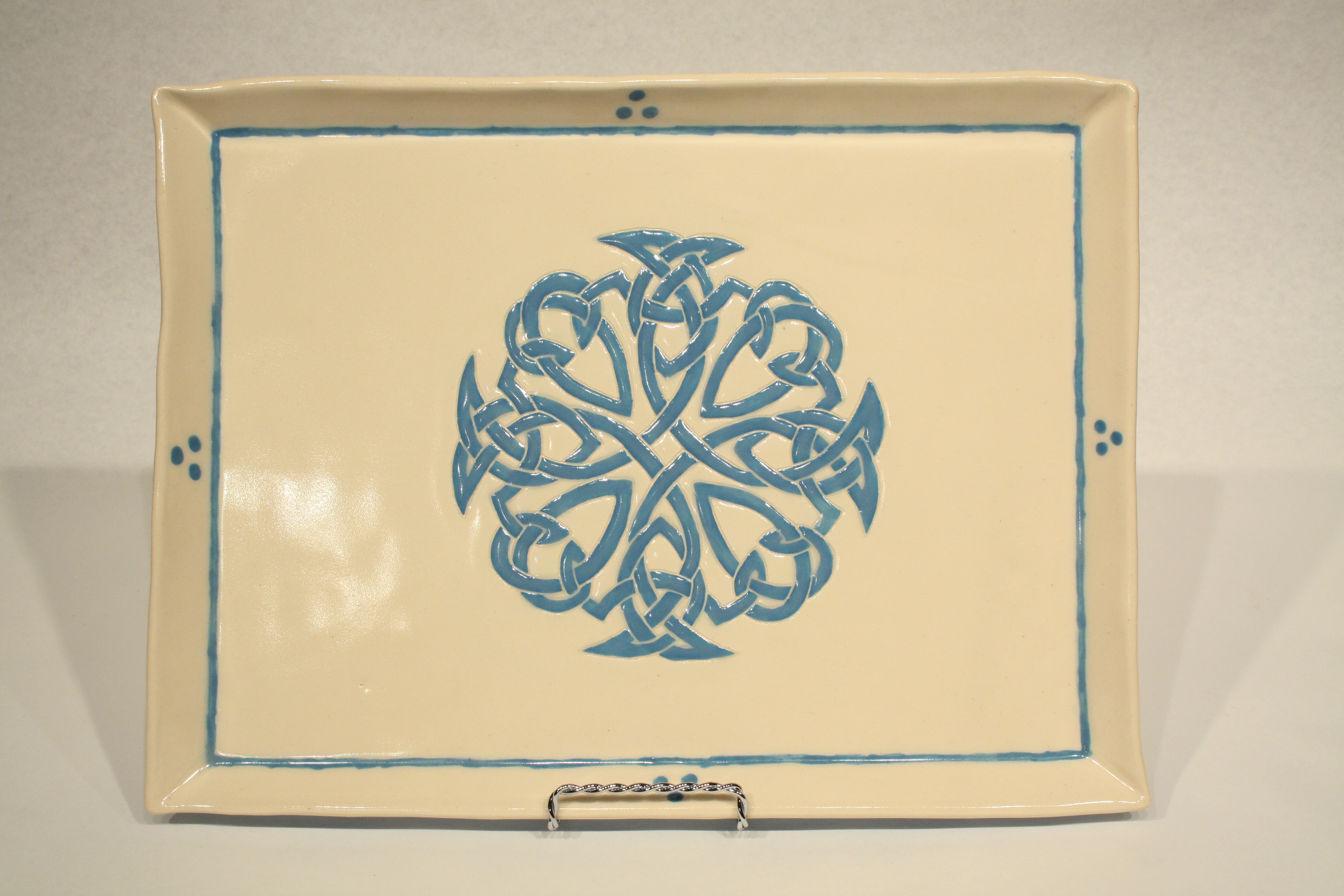 White ceramic plate with intricate blue Celtic knot design in center by Sophia Hart.