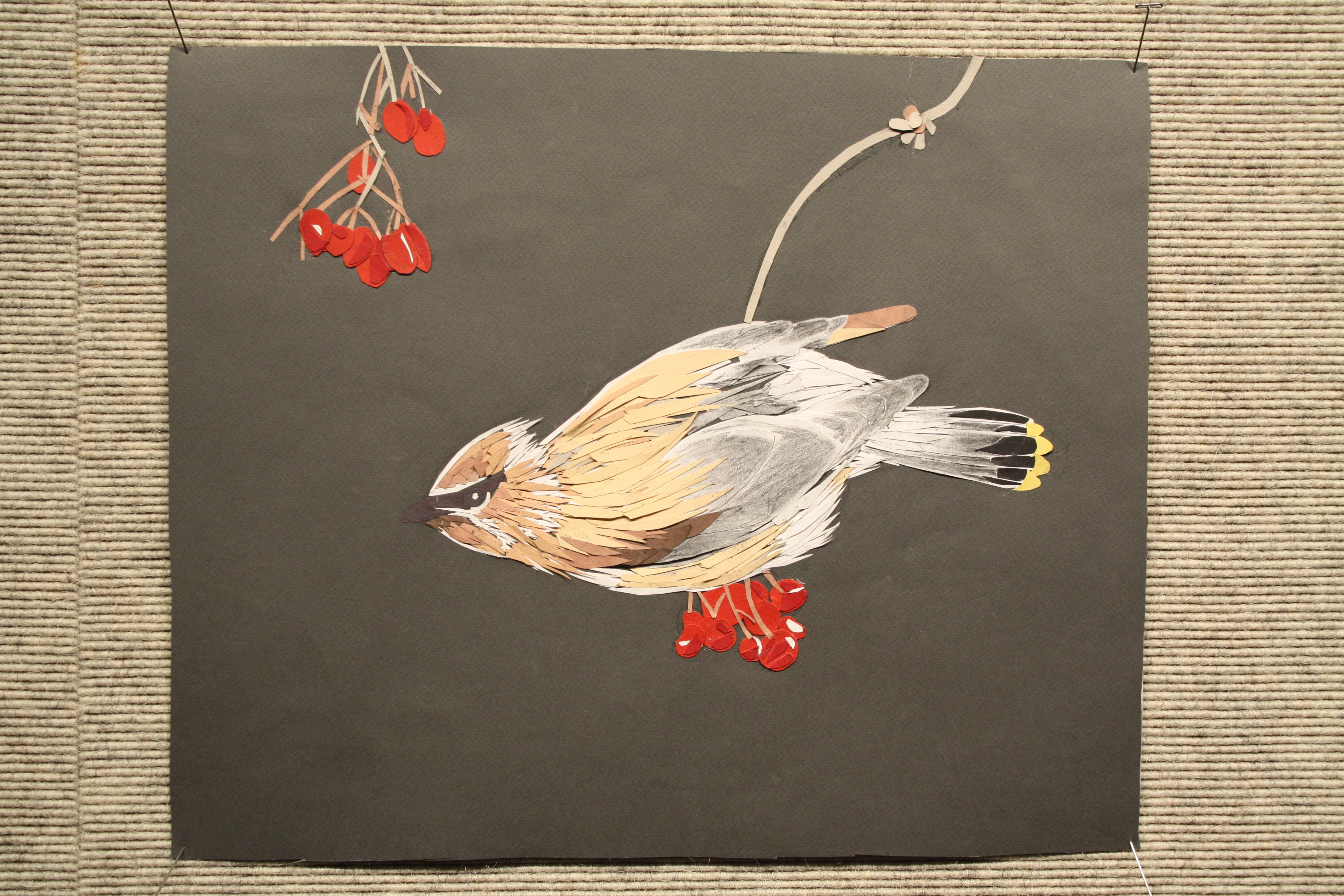 Paper cutout of goldfinch on a cherry tree branch.