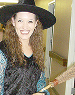 Photo of teacher wearing a witch's hat, black shirt, and holding a thin broom.